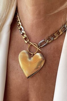 An oversized gold heart pendant hangs from a bold statement figaro link chain with a toggle clasp closure! Chunky Necklace Gold, Metal Heart Necklace With Chunky Chain, Chunky Heart Pendant Jewelry Gift, Gold Chunky Heart-shaped Jewelry, Chunky Heart-shaped Gold Jewelry, Chunky Heart Shaped Gold Jewelry, Chunky Metal Necklace With Heart Pendant, Trendy Heart Necklace With Chunky Chain For Valentine's Day, Chunky Metal Heart Pendant Necklace