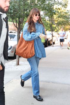 a woman walking down the street carrying a brown bag