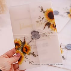 a hand holding a card with sunflowers on it and a button attached to the front