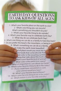 a child holding up a paper with the words earth day questions to ask kids of all ages