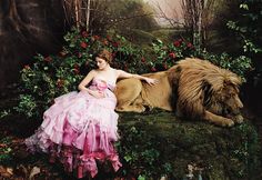 a woman in a pink dress sitting next to a lion