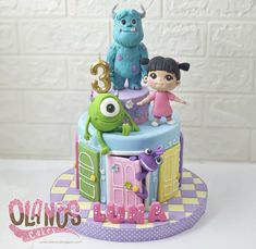 a birthday cake with monsters on top and two girls in the middle standing next to each other