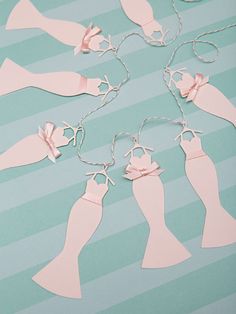 paper cutouts of dresses and shoes are on a blue striped table with silver chains