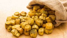 small pieces of bread sitting on top of a wooden table next to a burluck bag