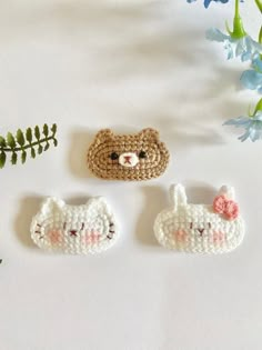 three small crocheted animals sitting on top of a white table next to flowers