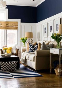 a living room with blue walls and white furniture, yellow flowers in vases on the coffee table