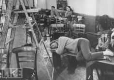 an old black and white photo of people in a room with many tables, chairs and ladders