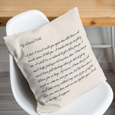 a pillow sitting on top of a white chair next to a wooden table with writing on it