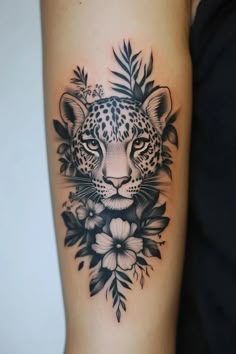 a woman's arm with a black and white tattoo on it, featuring a leopard surrounded by flowers