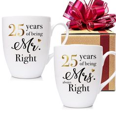 two coffee mugs are next to a gift box