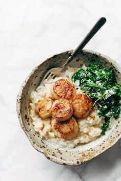 a bowl filled with rice and scallops next to greens