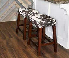 two stools sitting next to each other in front of a counter top with wood flooring