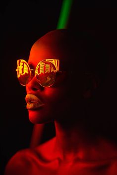 a woman wearing sunglasses with red light reflecting on her face