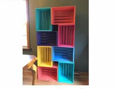 a multicolored bookcase sitting on top of a hard wood floor next to a window