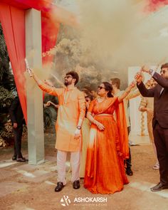 two men and one woman are standing in front of some people holding their hands up