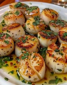 some scallops are sitting on a plate with sauce and garnishes