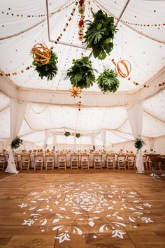 the inside of a wedding tent decorated with flowers and greenery