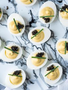 deviled eggs with black cavias and chives on a marble platter