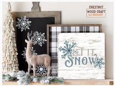 a wooden sign that says let it snow next to a deer and pine tree on a mantel