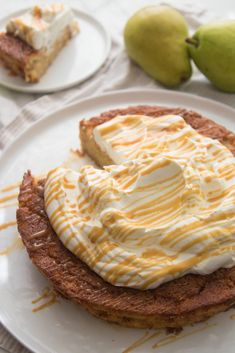 there is a dessert on the plate with whipped cream and pears in the background