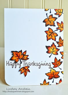 a white card with orange leaves on it and the words happy thanksgiving written in brown ink