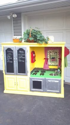 an outdoor play kitchen with chalkboards on the side and potted plants in it