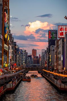 a river running through a city with lots of tall buildings on both sides and boats in the water