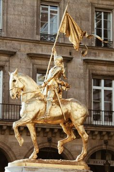 a statue of a man riding on the back of a horse next to a tall building