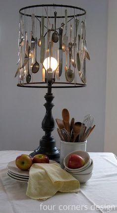 a lamp that is on top of a table with some fruit and spoons in it