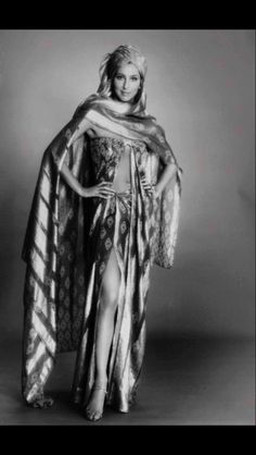 an old photo of a woman wearing a dress and shawl with her hands on her hips