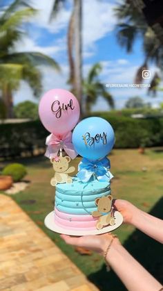 a person holding up a cake with balloons on it