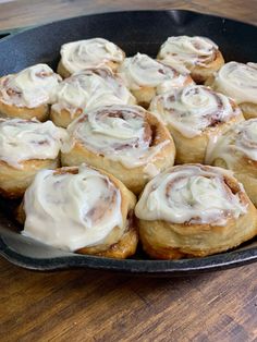 a pan filled with cinnamon rolls on top of a wooden table