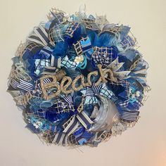 a wreath with the word boo spelled out in blue, white and silver ribbons hanging on a wall