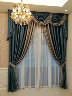 a chandelier hanging from the ceiling next to a window with curtains and drapes