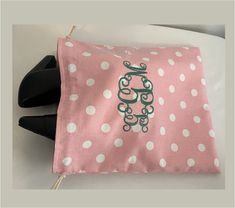 a pink and white polka dot bag with green monogrammed letters on the front