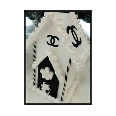 a white and black house shaped cake with flowers on the front, decorated in icing