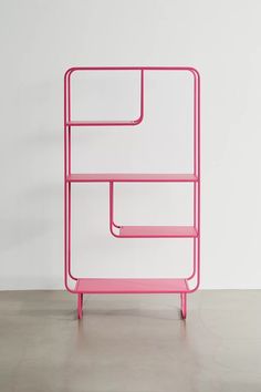 a pink shelf sitting on top of a cement floor next to a white wall,