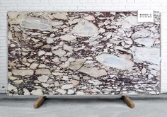 a white and brown marble slab sitting on top of a wooden stand in front of a brick wall