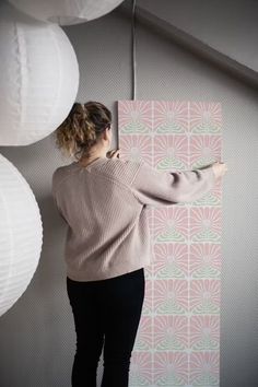 a woman standing in front of a wall with paper lanterns