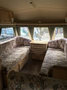 the inside of a recreational vehicle with couches and tables in front of two windows