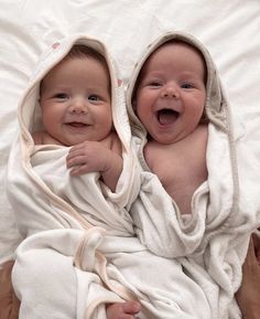 two babies are wrapped in blankets and smiling