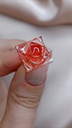 a woman's hand holding a red rose shaped ring