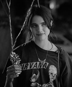 black and white photograph of a woman holding flowers in front of her face while wearing an nirvana t - shirt