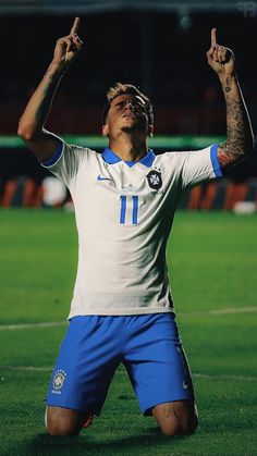 a man sitting on top of a soccer field holding his hands up in the air