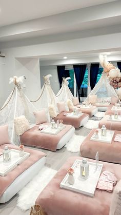 a room filled with lots of pink couches covered in white blankets and pillows on top of each other