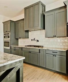 a kitchen with gray cabinets and marble counter tops