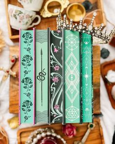 several books with crowns on top of them sitting on a wooden table next to other items