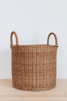 a wicker basket sitting on top of a wooden table next to a white wall