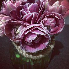 purple flowers are in a glass vase on the table