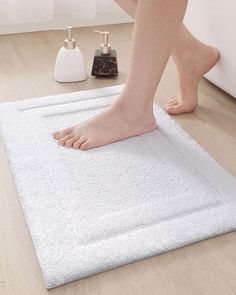 a person standing on top of a white rug next to a bathtub and toilet